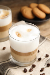 Obraz na płótnie Canvas Delicious latte macchiato and coffee beans on wooden table