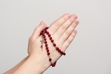 folded hands of a young man holding a rosary during of a pray