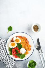 Breakfast. Potatoes latkes with sour cream, spinach salad, tomatoes and boiled eggs on light background. Delicious food for breakfast. Top view.