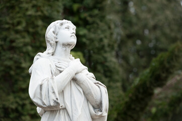 Sculpture of a grieving woman looking up with arms folded on her chest