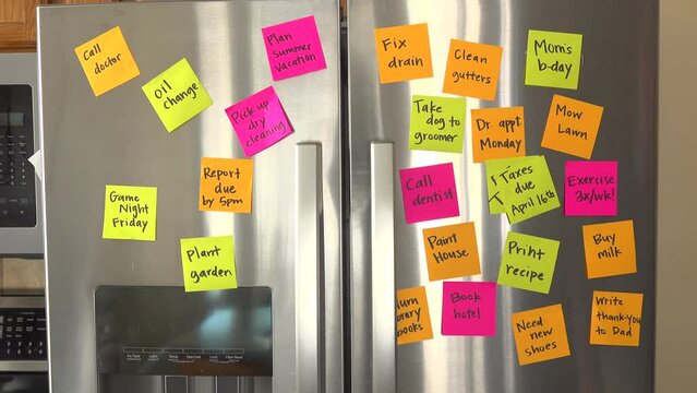 Refrigerator Door Filled With Reminder Notes and Hand Adds Taxes Due April 16th Memo Over File Taxes Memo