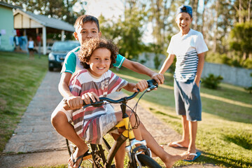 First rule of brotherhood Ride a bike together. Shot of happy young brothers riding a bicycle together in their backyard.