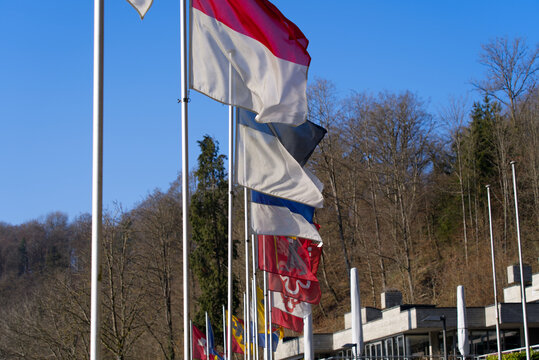 Flags of all Swiss Cantons at border of natural pool of famous Rhine Falls on s sunny spring day. Photo taken March 5th, 2022, Zurich, Switzerland.