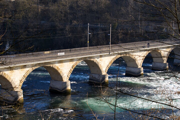 Aerial view of railway viaduct at famous Rhine Falls with rocks on a sunny spring day, focus on...