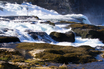 Famous Rhine Falls with rocks, spray and splashing water on a sunny spring day. Photo taken March 5th, 2022, Zurich, Switzerland.