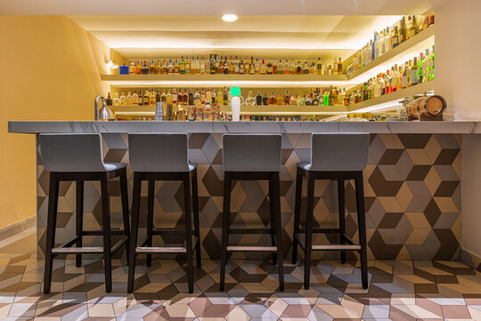 Modern bar counter with stools and different bottles of alcohol