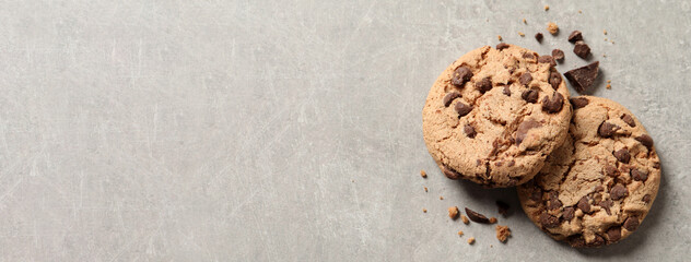 Two delicious chocolate chip cookies on grey marble table, top view with space for text. Banner design