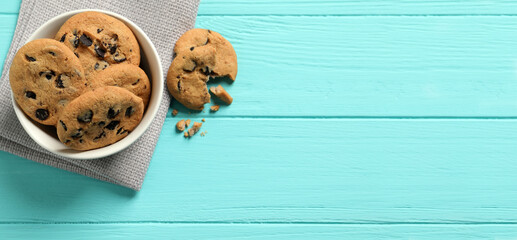 Bowl with many delicious chocolate chip cookies on turquoise wooden table, flat lay with space for text. Banner design