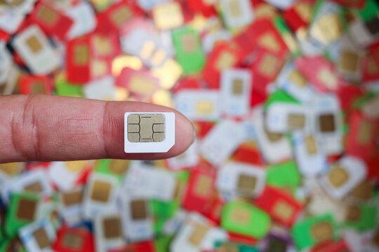 The gold phone sim card chip placed on the young man's finger is a sim card chip available in Thailand and the size of the sim card is also the same standard all over the world.