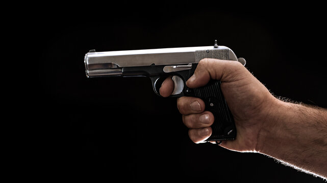 Old russian semiautomatic pistol (Tokarev) held in right hand on black background. 