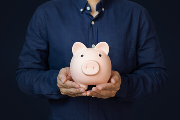 Man holding  piggy bank on blue background. Concept for invest and saving success in the future goal