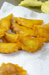 Vertical closeup of freshly fried dumplings on a tissue against raw ones