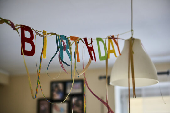 Colorful birthday decoration hanging from a lamp in a house