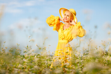 happy girl in a yellow dress holds sunflower flowers in a field of sunflowers against the sky. concept for farmers 