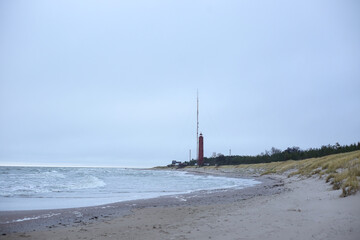 Seaside view of Baltic sea and red lighthouse in background.