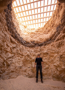 Man standing in rocky hole and looking through lattice