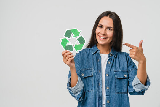 Young caucasian woman girl eco-activist holding pointing at recycling logo sign for sorting garbage paper plastic, environmental conservation saving planet from contamination, renewable energy sources
