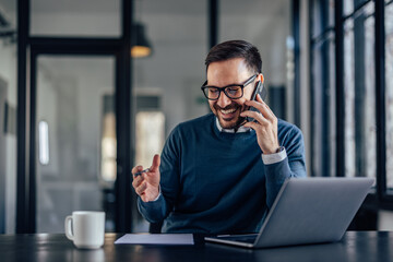 Smiling businessman, talking to someone over the phone, laughing.