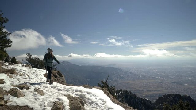 Female hiker walks along cliffside overlooking Albuquerque New Mexico, 4K