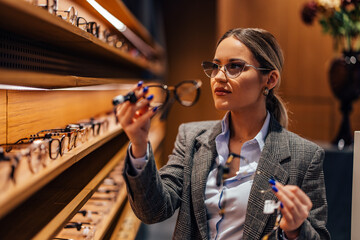 Close up of a young woman, searching for a good pair of glasses.