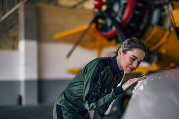 Lovely cuacasian female aviator, gently feeling the wing of the