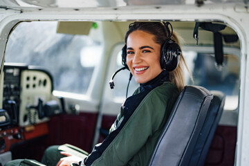 Portrait of smiling caucasian woman aviator, talking to the people at the radio station.