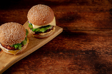 Two hamburgers on a wooden background. Big and small cheeseburger. Hamburger day.