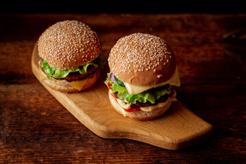 Two hamburgers on a wooden background. Big and small cheeseburger. Hamburger day.