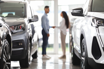 Unrecognizable man and woman shaking hands at auto showroom