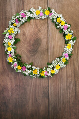Spring wreath with flowers and hawthorn blossom. Flora and leaves used in natural herbal plant medicine to treat a large variety of illnesses. On rustic wood background. Flat lay, top view. 