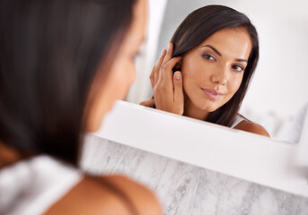 Not a hair out of place. Shot of a beautiful young woman looking at her face in the mirror.