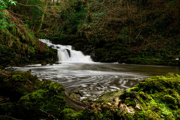 Mesmerizing view of the waterfall in the forest with dense greenery on a gloomy day
