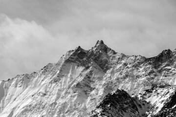 Grayscale of mountains under the cloudy sky