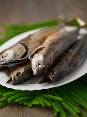 Freshly caught fish, young wild tuna smoked on white plate, vertical view