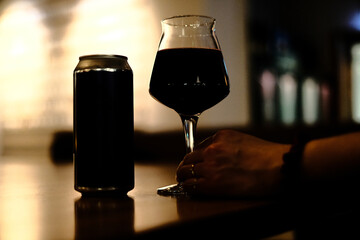 Closeup shot of the female hand holding a glass of wine placed on the wooden table at home
