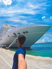 Portrait of a young black male tourist in front of a cruise ship on cloudy sky. African tourist on...
