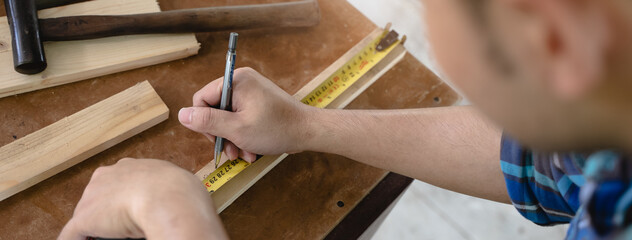 Hands of person doing diy project at home. Man measuring wood to doing cabinet craftworks as a hobby.