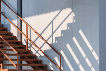 Sunlight and shadow on surface of the old metal staircase on gray sandwich panel wall outside of cold storage in industrial freezer warehouse area 