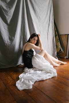 Woman in a nightgown sitting on the floor with a white sheet