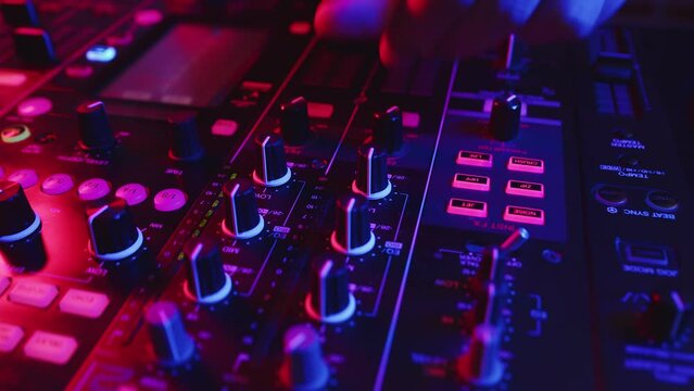 Closeup fingers of sound engineer tuning fader on mixing console. DJ adjusts volume on equipment in club. Person adjusts fader at mixing console