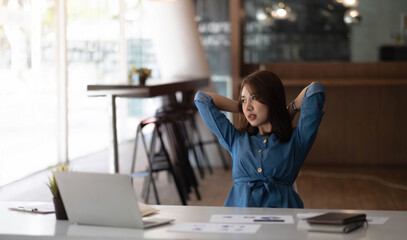 Asian woman enjoy and happy of relaxing at the office. Hold hands behind head concept of success future.