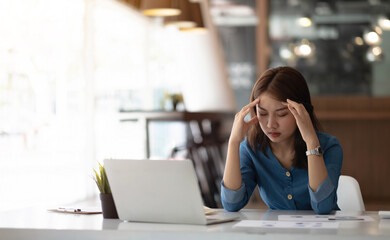 Image Asian woman are stressed, pain in their eyes, work with their laptop, taking notes at office.