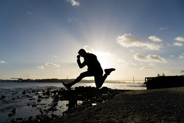 Fototapeta na wymiar Silhouette of a man jumping on the bank of the Tagus River at sunset