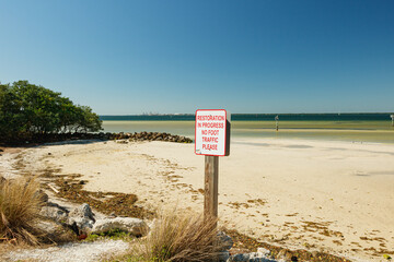Sign on the shore saying restoration in progress no foot traffic, please. Tampa, Florida coastline.