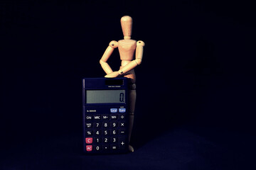 wooden mannequin is posing with a black pocket calculator