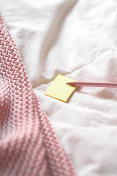 Closeup Of Yellow Notepaper With A Pencil On A White Fabric