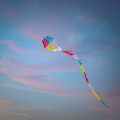 Colorful flying kite against a beautiful sunset - obrazy, fototapety, plakaty