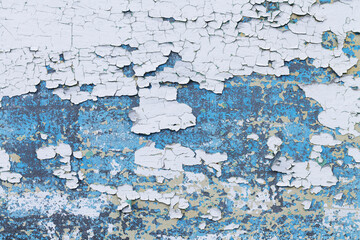 White and blue paint is peeling off on metal surface