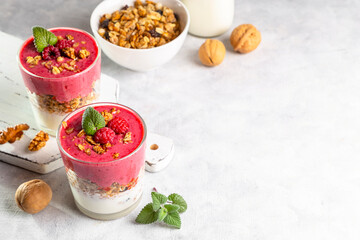 Yogurt, raspberry smoothie and homemade granola in a transparent glass. Healthy breakfast or snack. Copy space