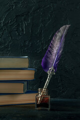 Feather quill pen with a vintage ink well and a stack of old books, a side view on a black background, the concept of writing